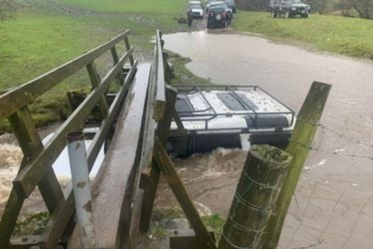 autos, cars, land rover, man’s land rover adventure ends stuck under a footbridge in floodwaters