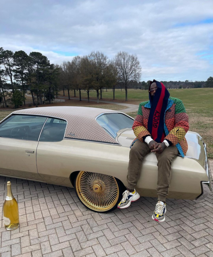 rick ross chills on the trunk of his 1971 chevrolet impala that's been guccified