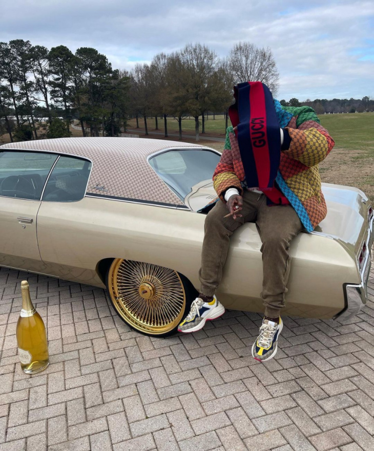 rick ross chills on the trunk of his 1971 chevrolet impala that's been guccified