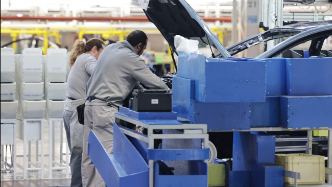 Renault factory: workers installing components from autonomous parts trolley
