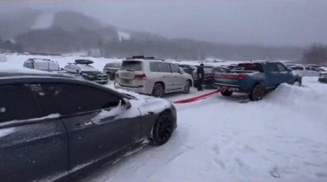 tesla model s tows a rivian r1t electric ute from the snow