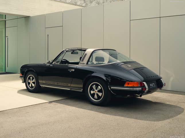 A black 1972 Porsche 911 Targa is parked in front of a modern house.