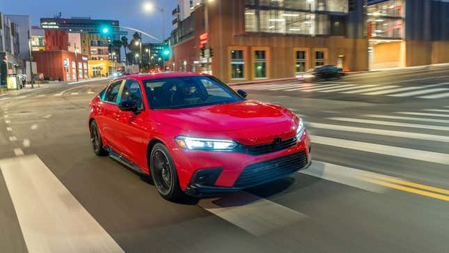 A photo of a red Honda Civic sedan at night time. 