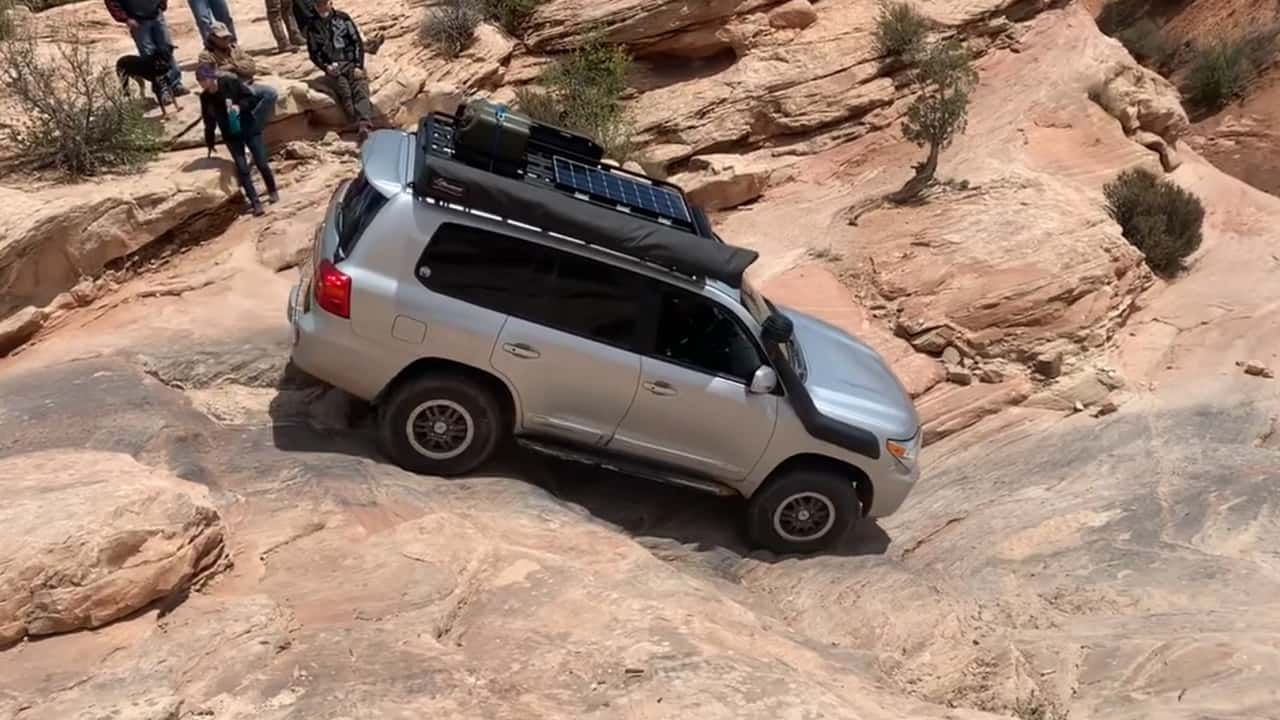 A Toyota Land Cruiser driving down a rock ledge.