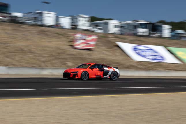 A red Audi R8 speeding down a raceway, the background blurring due to the speed of the car.
