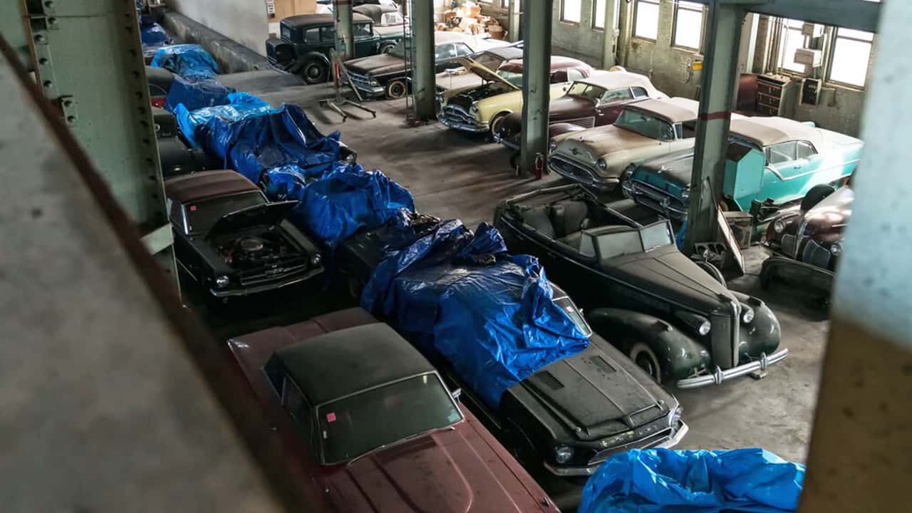 Classic cars abandoned in an old warehouse.