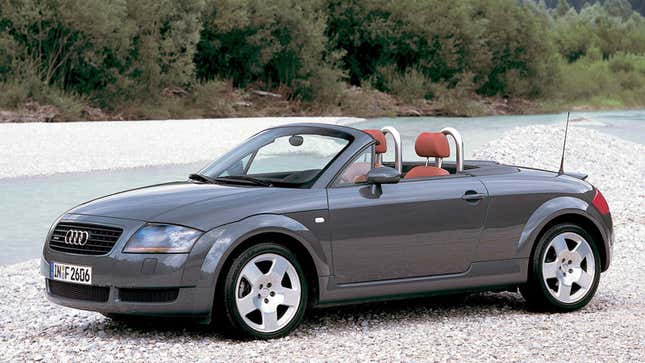 A photo of a grey Audi TT by a river. 